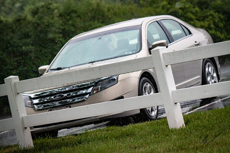 A car behind a fence in the rain